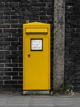 Gelber Postkasten vor einer Mauer