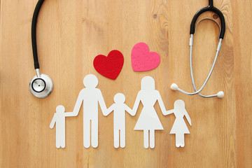 Health Insurance . concept image of Stethoscope and family on wooden table. top view