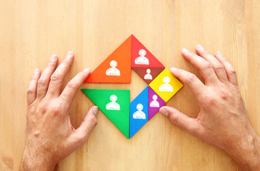 image of tangram puzzle blocks with people icons over wooden table ,human resources and management concept.