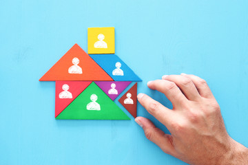 image of tangram puzzle blocks with people icons over wooden table ,human resources and management concept.