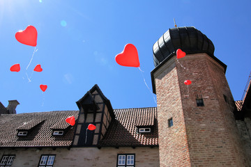 rote Luftballons in Herzform schweben in den Himmel 