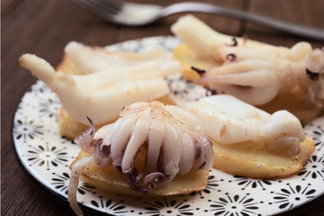 cuttlefish chopped on potatoes, on dark wooden board