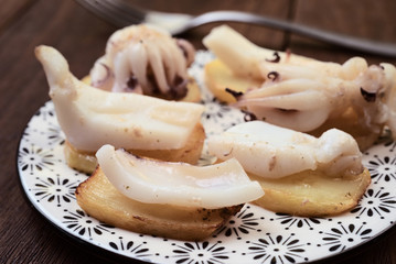 cuttlefish chopped on potatoes, on dark wooden board