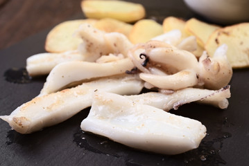 cuttlefish chopped on potatoes, on dark wooden board