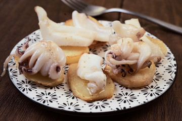 cuttlefish chopped on potatoes, on dark wooden board