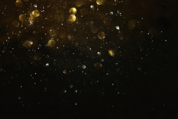 glitter vintage lights background. black and gold. de-focused.