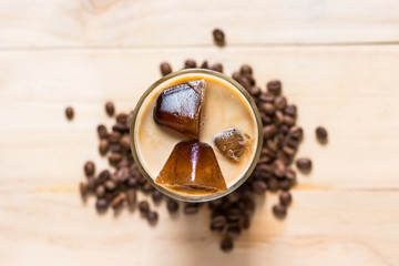 Espresso coffee frozen into ice cube mixed with milk on wooden background