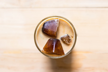 Espresso coffee frozen into ice cube mixed with milk on wooden background