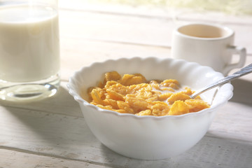Corn Flakes cereal in a bowl, glass with milk and cap with espresso coffee. Morning breakfast.