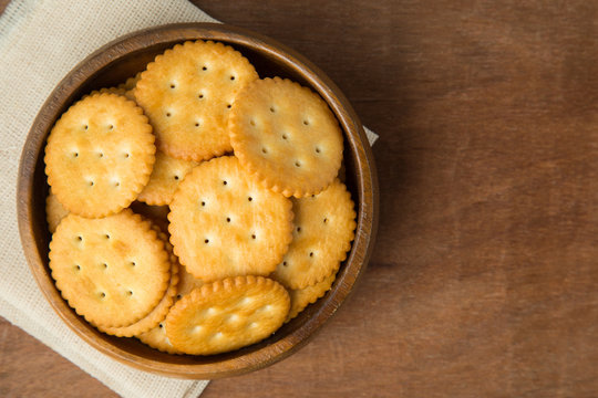 Round salted cracker cookies in wooden bowl putting on linen and wooden background.
