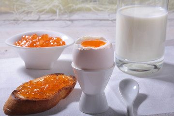 Morning Breakfast set with egg, orange jam on bread toast and milk in glass.