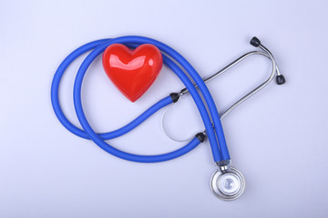 Stethoscope and red heart on white table with space for text.