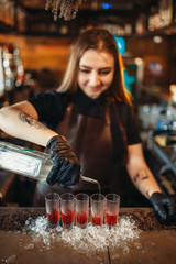 Female barman pours beverage into a glass