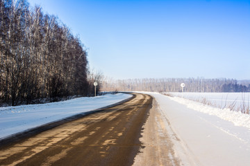Fototapeta na wymiar Beautiful winter landscape with asphalt road, forest and blue sky. Frozen wintry day and path drive. A lot of snow.