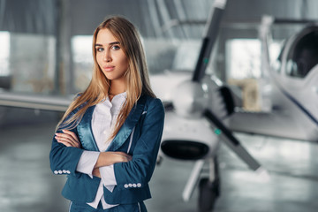 Stewardess against propeller plane in hangar