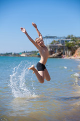 Fototapeta na wymiar Happy boy jumping into the sea