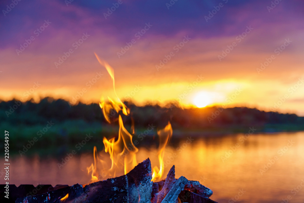 Wall mural bonfire by the river at sunset