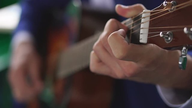 Man's hands playing acoustic guitar, close up