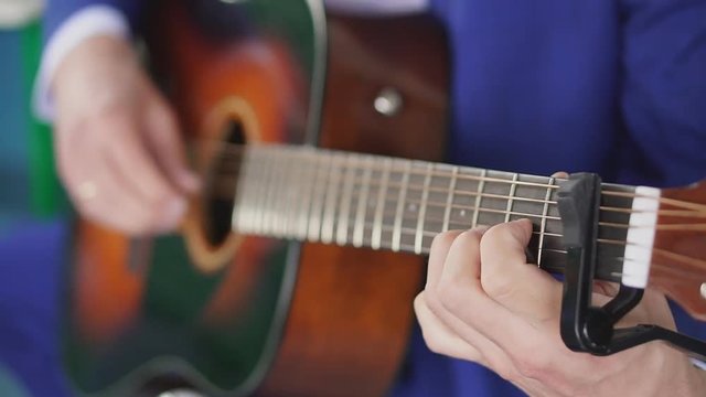 Man's hands playing acoustic guitar, close up