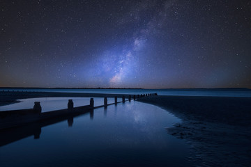 Vibrant Milky Way composite image over landscape of Beautiful long exposure beach