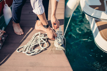 Male hands with boat rope. yachtsman tying sea knot while mooring the Yacht. Close up hands