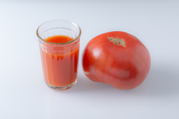 Large tomato and a glass of tomato juice