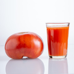 Large tomato and a glass of tomato juice