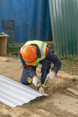 Worker cuts metal with angle grinder