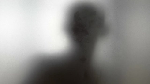 Dancing man behind frosted glass in 4k slow motion 60fps