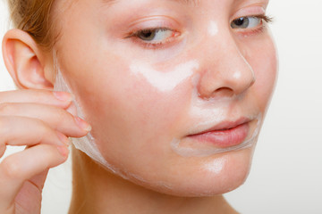 Woman removing facial peel off mask.