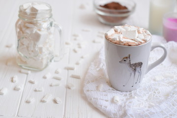 White cup with hot cocoa and marshmallow on the white wooden background