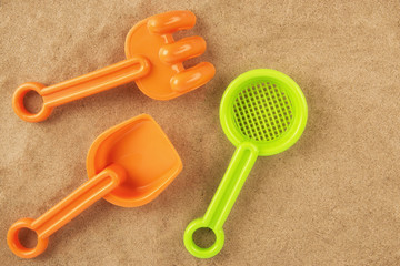 Rake and shovel toy on the beach, directly above. Copy space for your text.