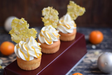 New-year vanilla capcakes with orange jelly and white chocolate cream. Orange decor with almonds and mandarin caramel