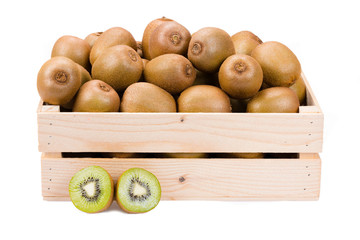 Wooden box filled with many ripe and fresh kiwi fruits and two half fruits in front of it isolated on white background