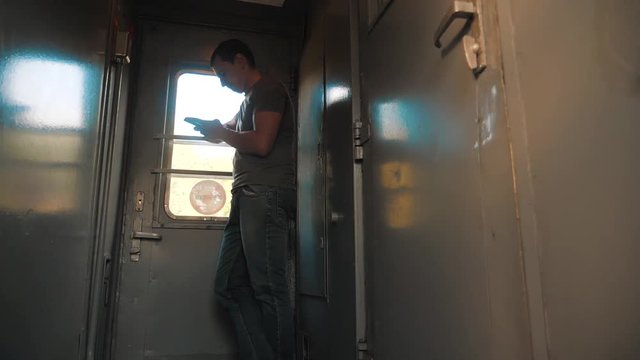 the man silhouette is standing on the train Railway carriage holding a smartphone and . slow motion video. man writes messages in the smartphone in the train social lifestyle media. man with