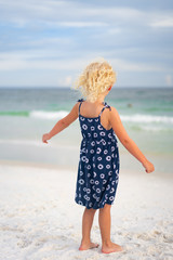 Little Girl on White Sand Beach with back turned and pretty dress