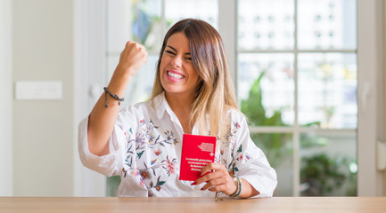 Young woman at home holding a passport of Switzerland annoyed and frustrated shouting with anger, crazy and yelling with raised hand, anger concept