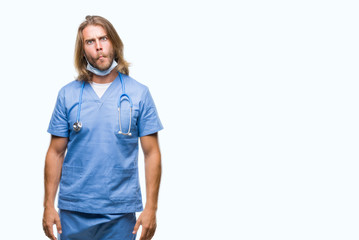 Young handsome doctor man with long hair over isolated background making fish face with lips, crazy and comical gesture. Funny expression.