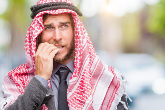 Young handsome arabian man with long hair wearing keffiyeh over isolated background looking stressed and nervous with hands on mouth biting nails. Anxiety problem.