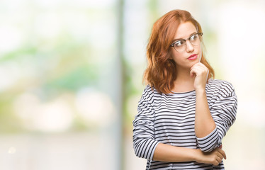 Young beautiful woman over isolated background wearing glasses with hand on chin thinking about question, pensive expression. Smiling with thoughtful face. Doubt concept.