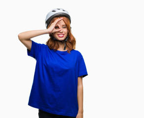 Young beautiful woman wearing cyclist helmet over isolated background doing ok gesture with hand smiling, eye looking through fingers with happy face.