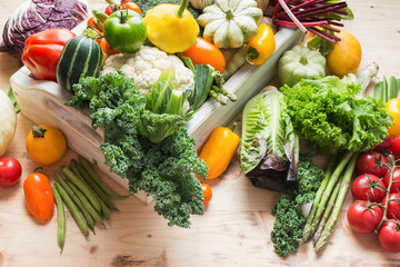 Assortment of fresh colorful organic vegetables in white tray on wooden pine table, food background, selective focus