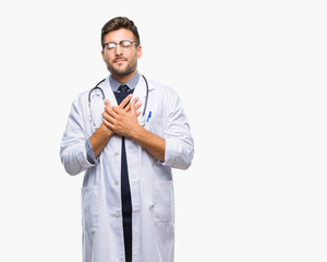Young handsome doctor man over isolated background smiling with hands on chest with closed eyes and grateful gesture on face. Health concept.