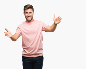 Young handsome man over isolated background looking at the camera smiling with open arms for hug. Cheerful expression embracing happiness.