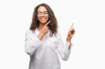 Beautiful young hispanic woman smiling and looking at the camera pointing with two hands and fingers to the side.