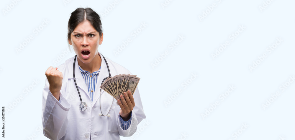 Sticker Young hispanic doctor woman holding dollars annoyed and frustrated shouting with anger, crazy and yelling with raised hand, anger concept