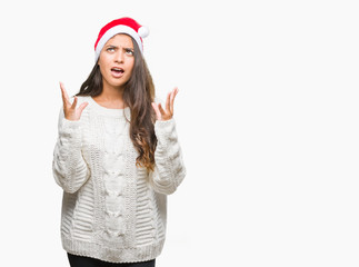 Fototapeta na wymiar Young arab woman wearing christmas hat over isolated background crazy and mad shouting and yelling with aggressive expression and arms raised. Frustration concept.