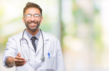 Adult hispanic doctor man over isolated background smiling friendly offering handshake as greeting and welcoming. Successful business.