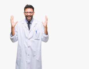 Adult hispanic scientist or doctor man wearing white coat over isolated background celebrating mad and crazy for success with arms raised and closed eyes screaming excited. Winner concept