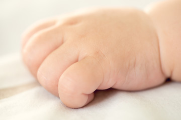 Close view of the closed hand of a newborn baby on bright background